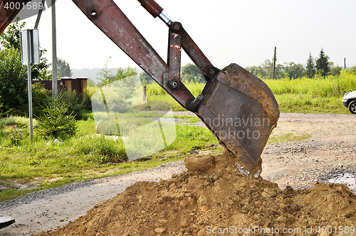 Image of Excavator bucket digging a trench in the dirt ground