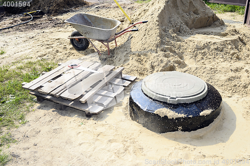 Image of Construction site with new armed manholes, cart, sand and equipm