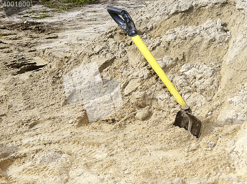 Image of Yellow shovel stands in a pile of building sand