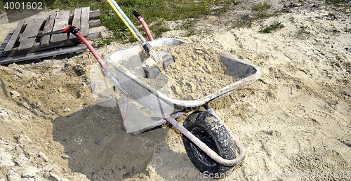 Image of A pile of sand, a shovel and a construction truck for transporta