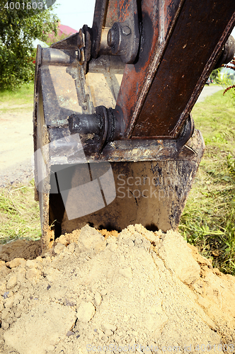 Image of Excavator bucket digging a trench in the dirt ground