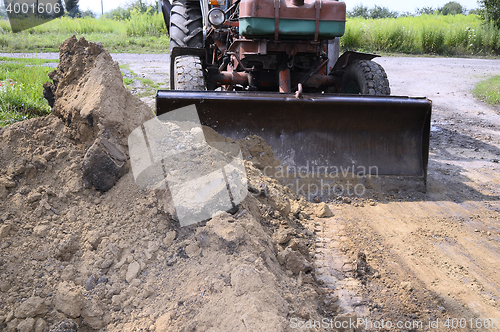 Image of Excavator bucket digging a trench in the dirt ground