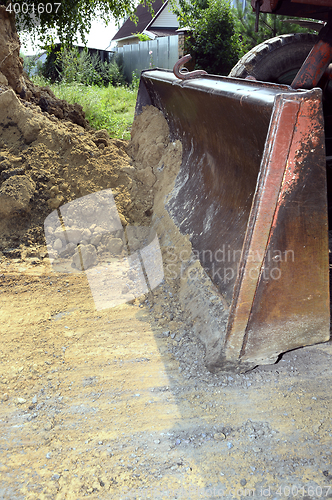 Image of Excavator bucket digging a trench in the dirt ground