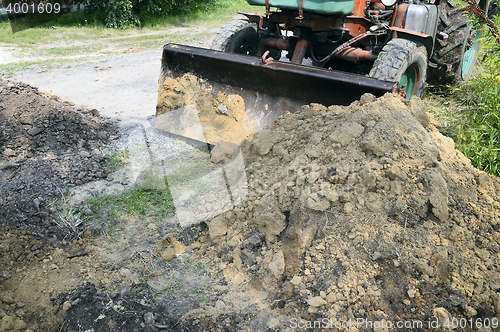 Image of Excavator bucket digging a trench in the dirt ground