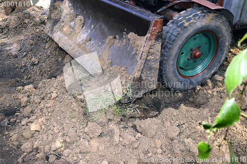 Image of Excavator bucket digging a trench in the dirt ground