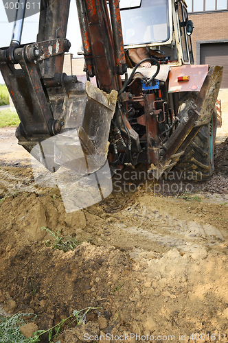 Image of Excavator bucket digging a trench in the dirt ground