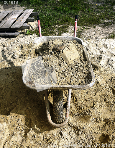 Image of A pile of sand, a shovel and a construction truck for transportation of goods