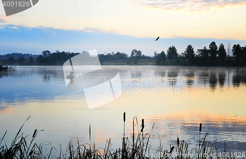 Image of A fisherman in a boat sailing in the morning mist