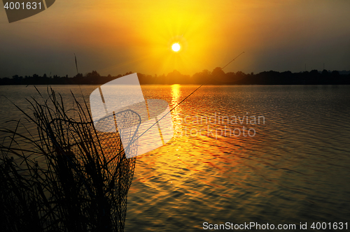 Image of Fishing rod and tank against the sunset on the lake fishing