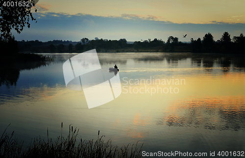 Image of A fisherman in a boat sailing in the morning mist