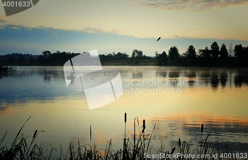 Image of A fisherman in a boat sailing in the morning mist