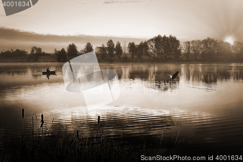 Image of A fisherman in a boat sailing in the morning mist