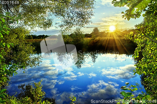 Image of Sunrise over the river in the summer with reflection of clouds i