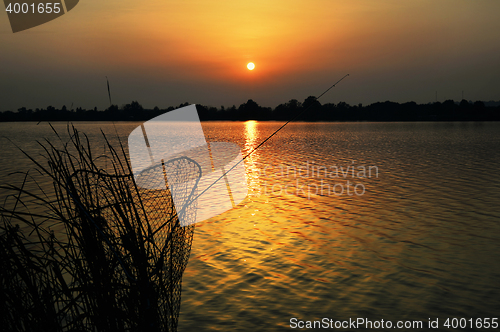 Image of Fishing rod and tank against the sunset on the lake fishing