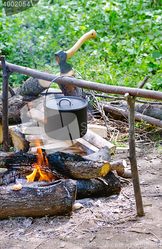 Image of Tourist pot of water hanging over a fire of wood in the Camping