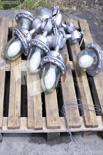 Image of Used in the production of waste lamps are stacked on a wooden pallet on the floor