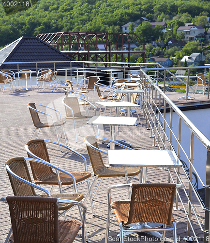 Image of Wicker chairs with metal legs and racks are in an open cafe area