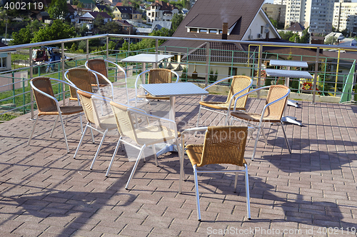Image of Wicker chairs with metal legs and racks are in an open cafe area