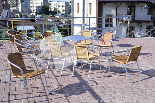 Image of Wicker chairs with metal legs and racks are in an open cafe area