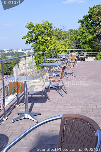 Image of Wicker chairs with metal legs and racks are in an open cafe area