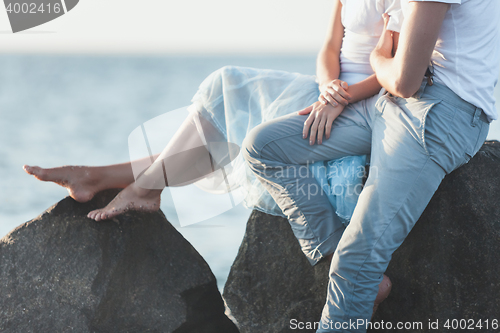 Image of Happy young romantic couple relaxing on the beach and watching the sunset