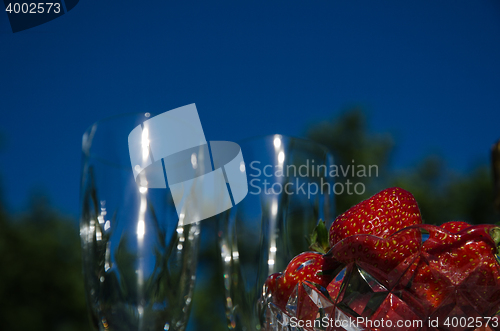 Image of Strawberries and two blurred glasses outdoors