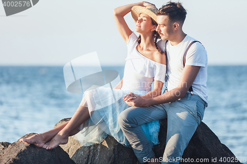 Image of Happy young romantic couple relaxing on the beach and watching the sunset