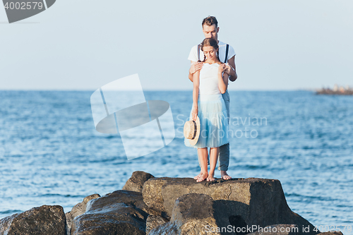 Image of Happy young romantic couple relaxing on the beach and watching the sunset