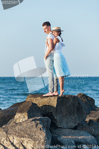 Image of Happy young romantic couple relaxing on the beach and watching the sunset