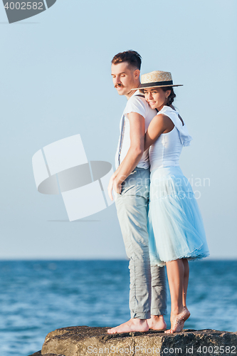 Image of Happy young romantic couple relaxing on the beach and watching the sunset