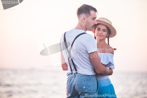 Image of Happy young romantic couple relaxing on the beach and watching the sunset