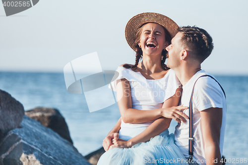 Image of Happy young romantic couple relaxing on the beach and watching the sunset