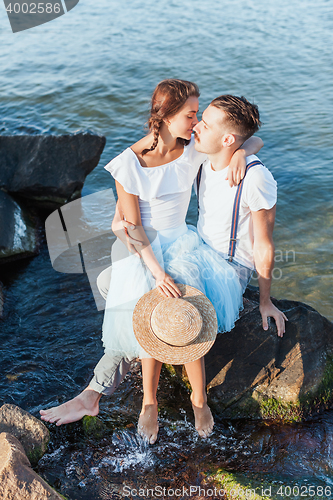 Image of Happy young romantic couple relaxing on the beach and watching the sunset