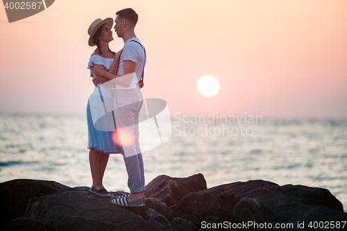 Image of Happy young romantic couple relaxing on the beach and watching the sunset