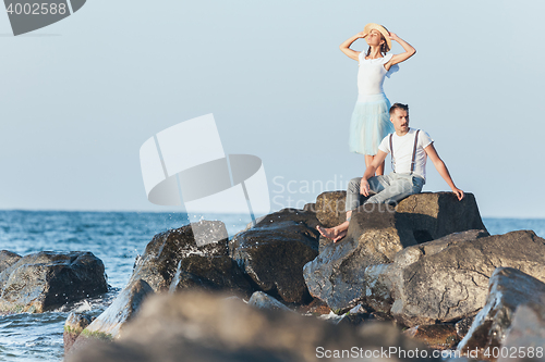 Image of Happy young romantic couple relaxing on the beach and watching the sunset