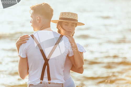 Image of Happy young romantic couple relaxing on the beach and watching the sunset