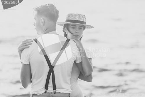Image of Happy young romantic couple relaxing on the beach and watching the sunset