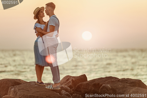 Image of Happy young romantic couple relaxing on the beach and watching the sunset