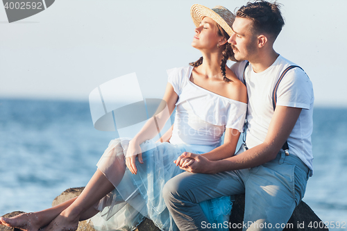 Image of Happy young romantic couple relaxing on the beach and watching the sunset