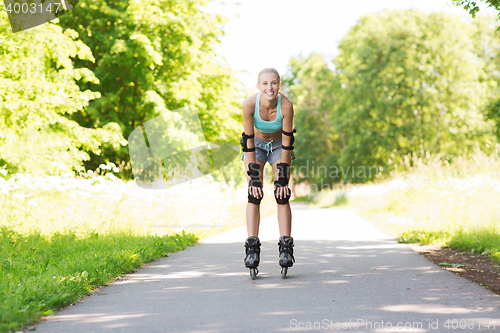 Image of happy young woman in rollerblades riding outdoors