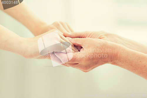 Image of close up of senior and young woman holding hands