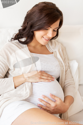 Image of happy pregnant woman lying on bed at home