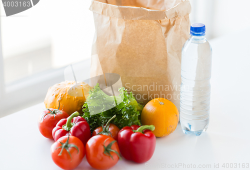 Image of close up of paper bag with vegetables and water