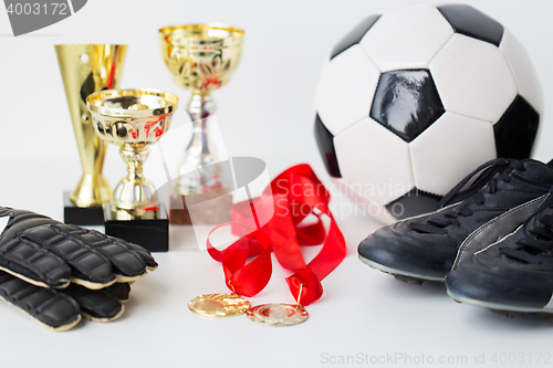 Image of close up of football, boots, gloves, cup and medal