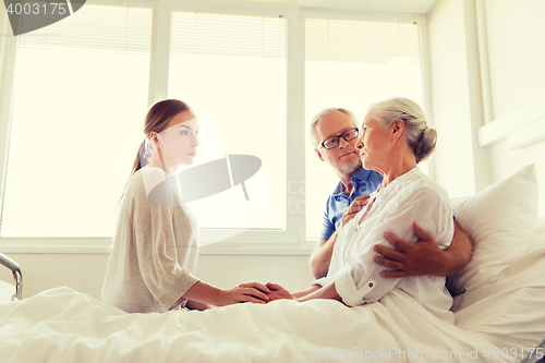 Image of family visiting ill senior woman at hospital