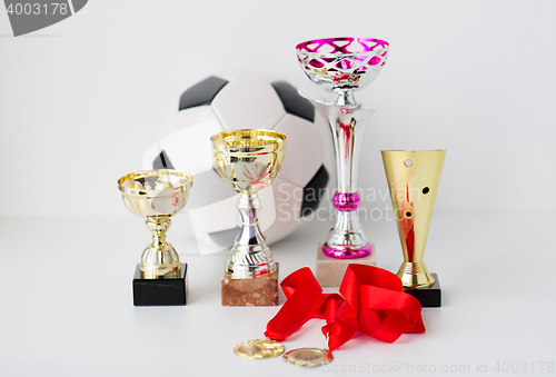 Image of close up of football ball, golden cups and medals