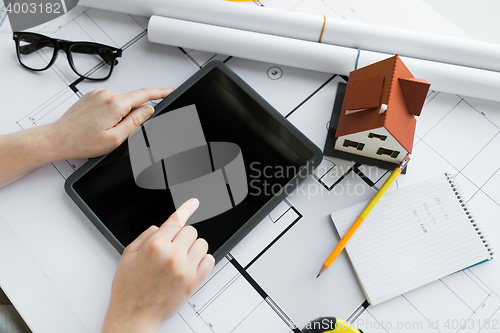 Image of close up of hand with blueprint and tablet pc