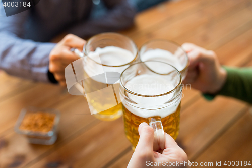 Image of close up of hands with beer mugs at bar or pub