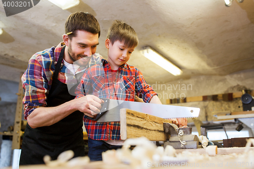 Image of father and son with saw working at workshop