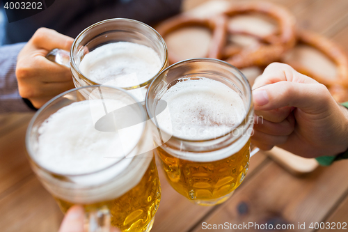 Image of close up of hands with beer mugs at bar or pub